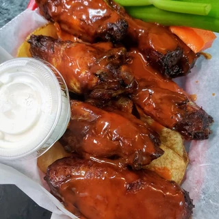 Saucy chicken wings served with celery, carrots, and a side of dip, perfect for a flavorful appetizer or meal
